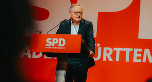 Der Landesvorsitzende der SPD Baden-Württemberg Andreas Stoch spricht von einem Rednerpult. Am Pult und hinter ihm auf der Leinwand weiß auf rot das Logo der SPD Baden-Württemberg.